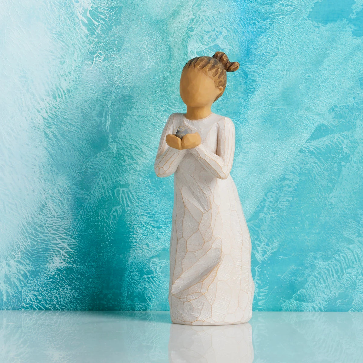 Willow Tree Nurture, 5.5”h hand-painted standing resin figure in cream dress, holding baby bluebird, in front of cerulean painting