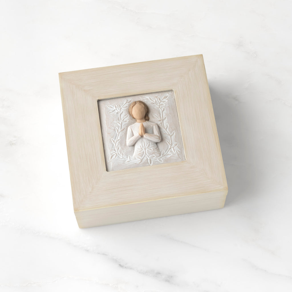 Cream square wood box with hinged lid, carving on lid of female in cream dress with hands in prayer position, surrounded by leaves and vines