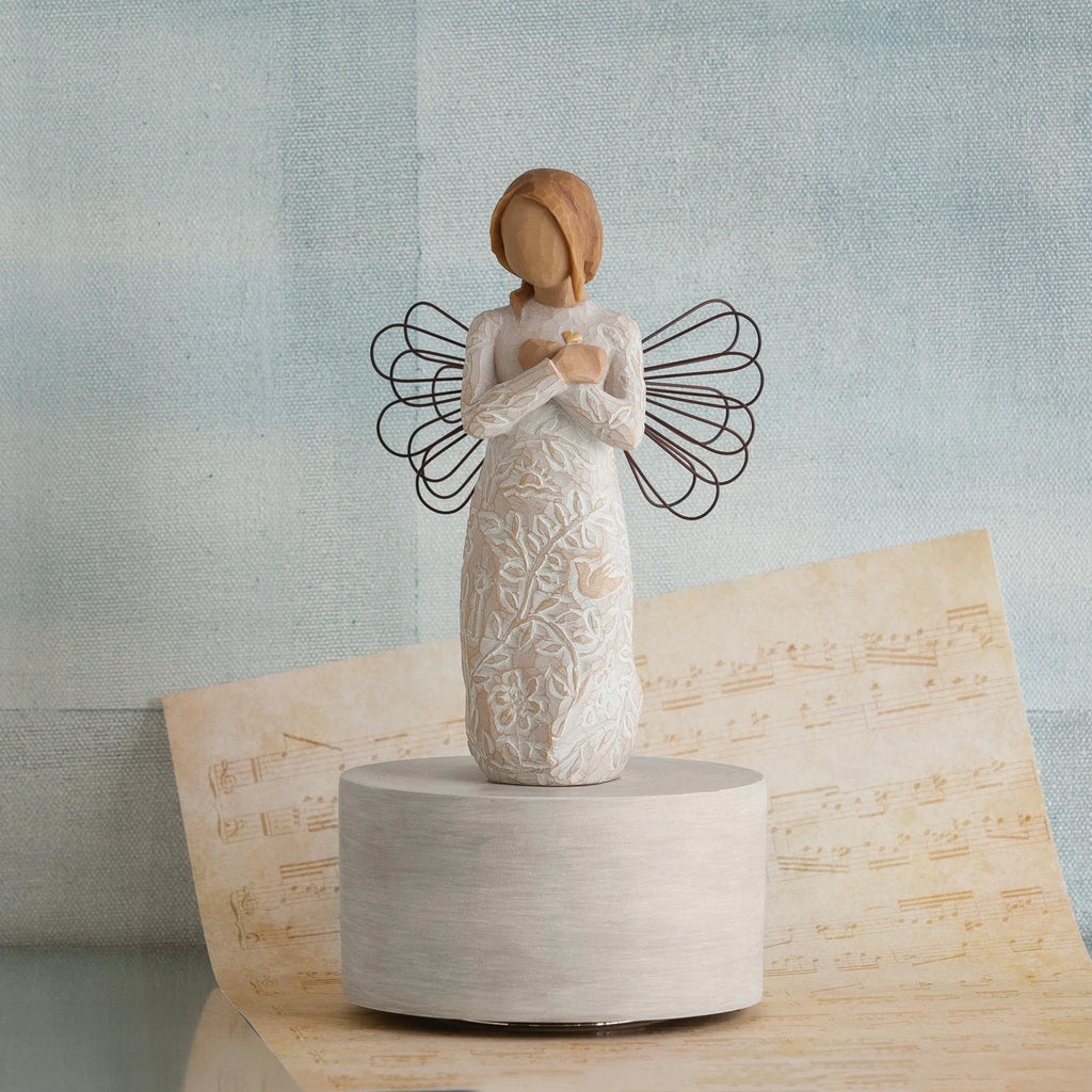 Standing faceless angel figurine in white dress with black wire wings - she is standing on round white stand with music sheet and blue background