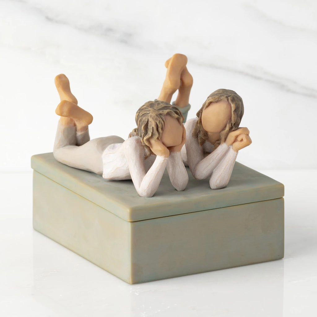 Front/long side view of closed rectangular blue-gray resin box, box; sculpture of two reclining girls on box lid