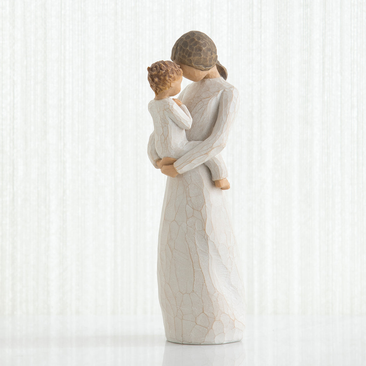 Mother figurine in white dress with brunette hair holding baby in white