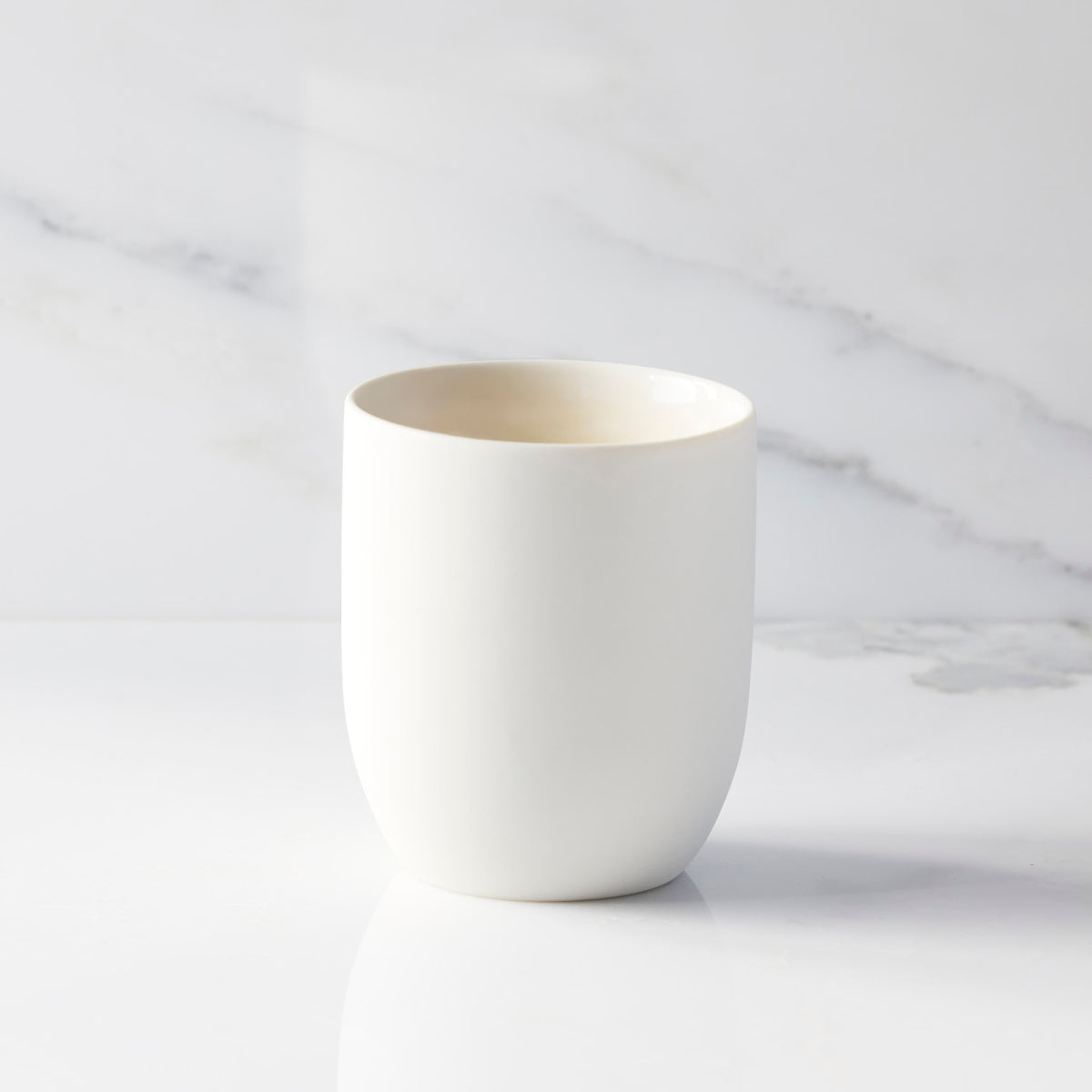 Back view of unglazed off-white tapered cylinder ceramic candle vessel