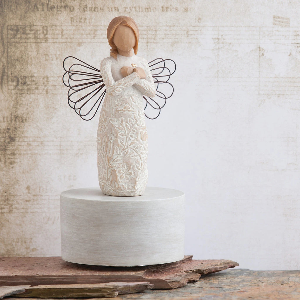 Willow Tree Remembrance Musical, 7.5”h hand-painted resin angel figure in cream dress carved with symbols of nature, wire wings, crossed hands under small gold-leaf heart, atop round, cream base containing musical element, in front of cream painting