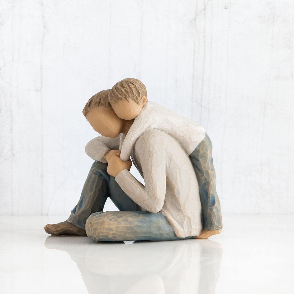 Faceless man figurine with little boy's arms around him - both weraing white shirts with blue jeans