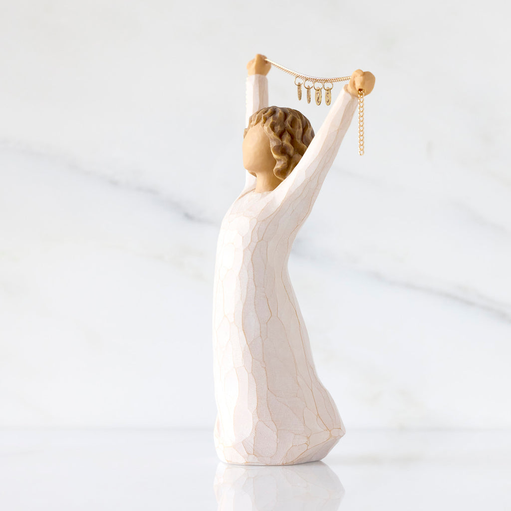 Willow Tree Courage 2025, 6”h hand-painted standing figure in cream dress holding aloft a gold chain with 2025 etched on gold medallions