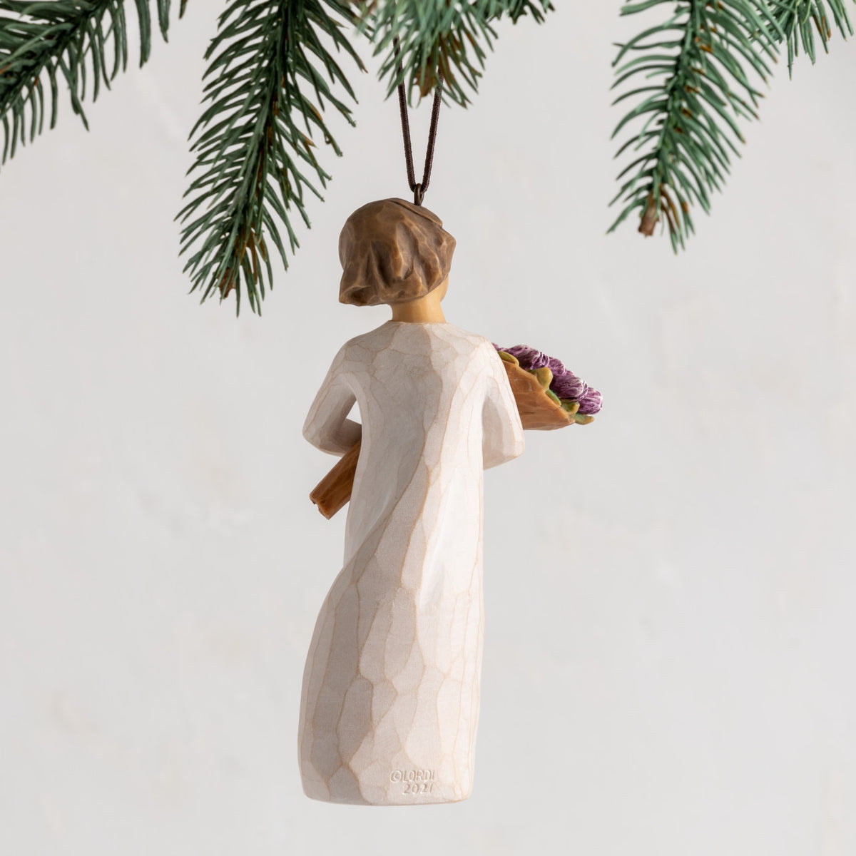 Back view: female figure with brown hair in cream dress holding bouquet of purple tulips; hook and loop affixed to head