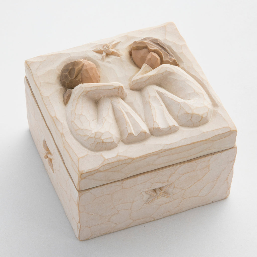 Close view of cream box with carved in image of two brunette girl figurines sitting down