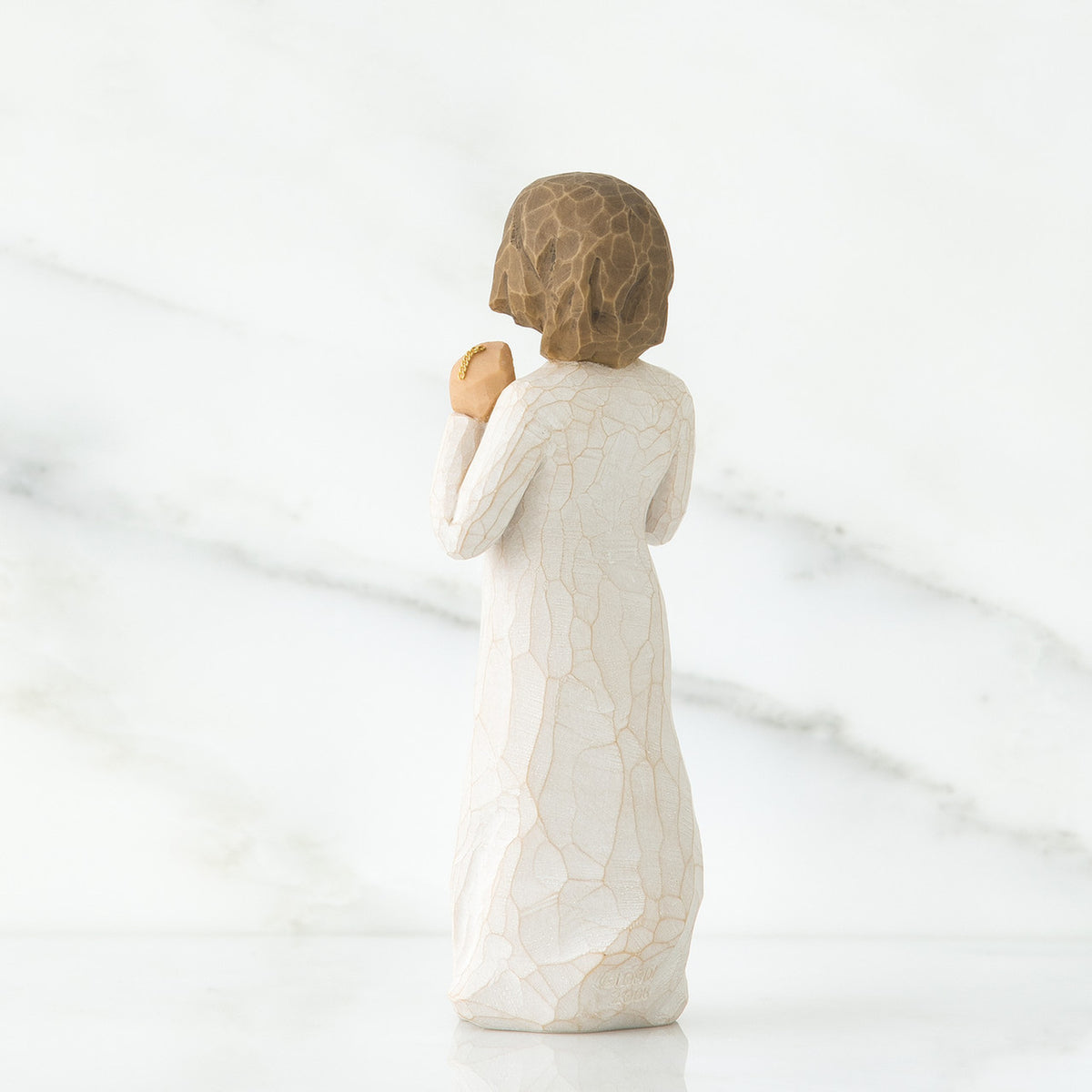 Back view of brunette girl figurine in white dress