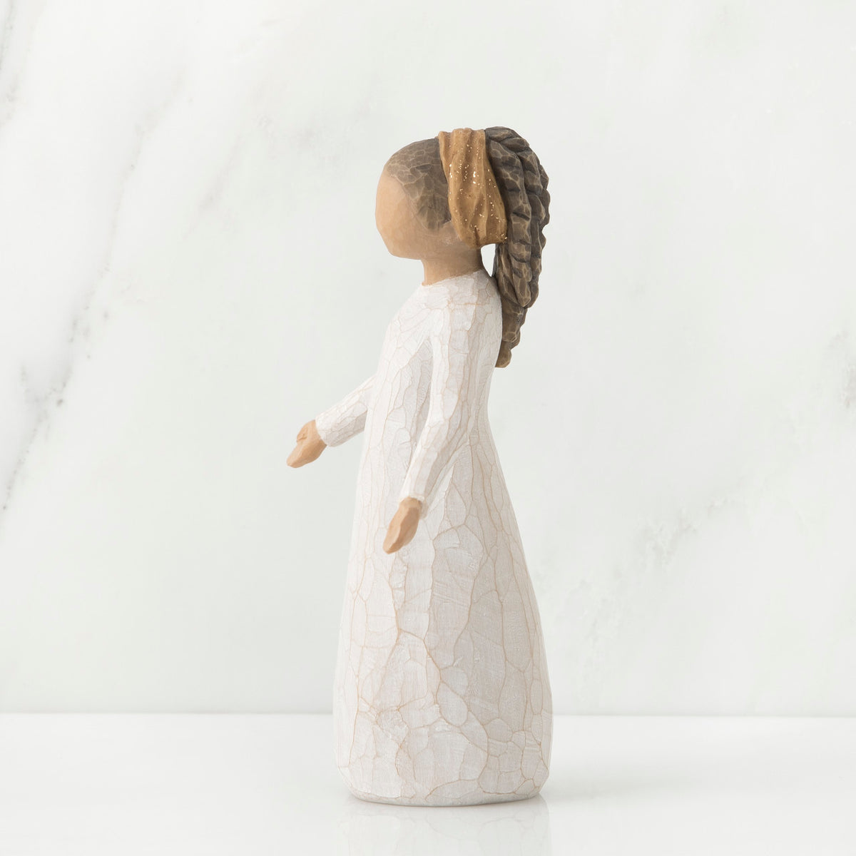 Side view of brunette girl figurine with braided ponytail wearing white dress standing up