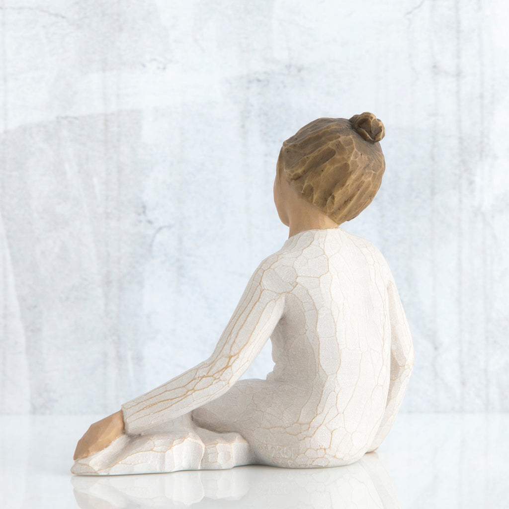 Back view of brunette girl figurine in white sitting down