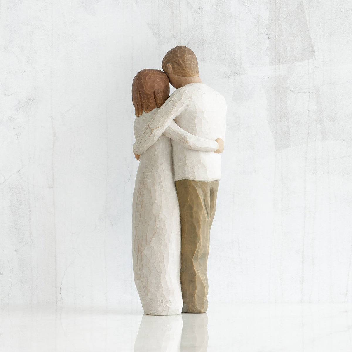 Man and woman figurines - back view - hugging another