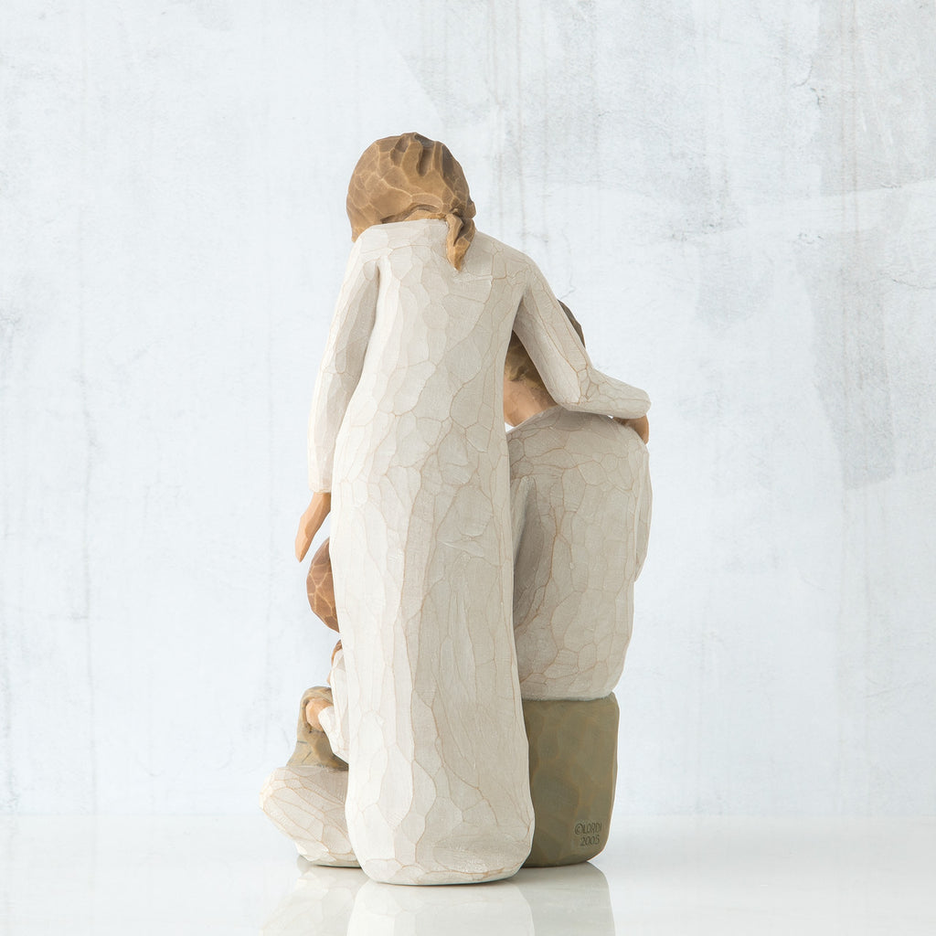 Back view of brunette woman in white dress standing up with arm over man figurine sitting down