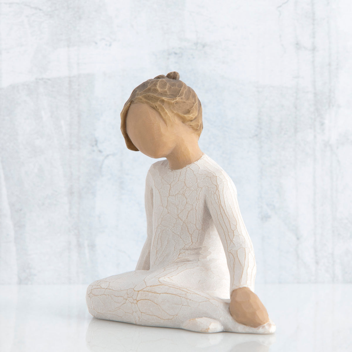 Small young brunette girl figurine in white siting down looking to the side