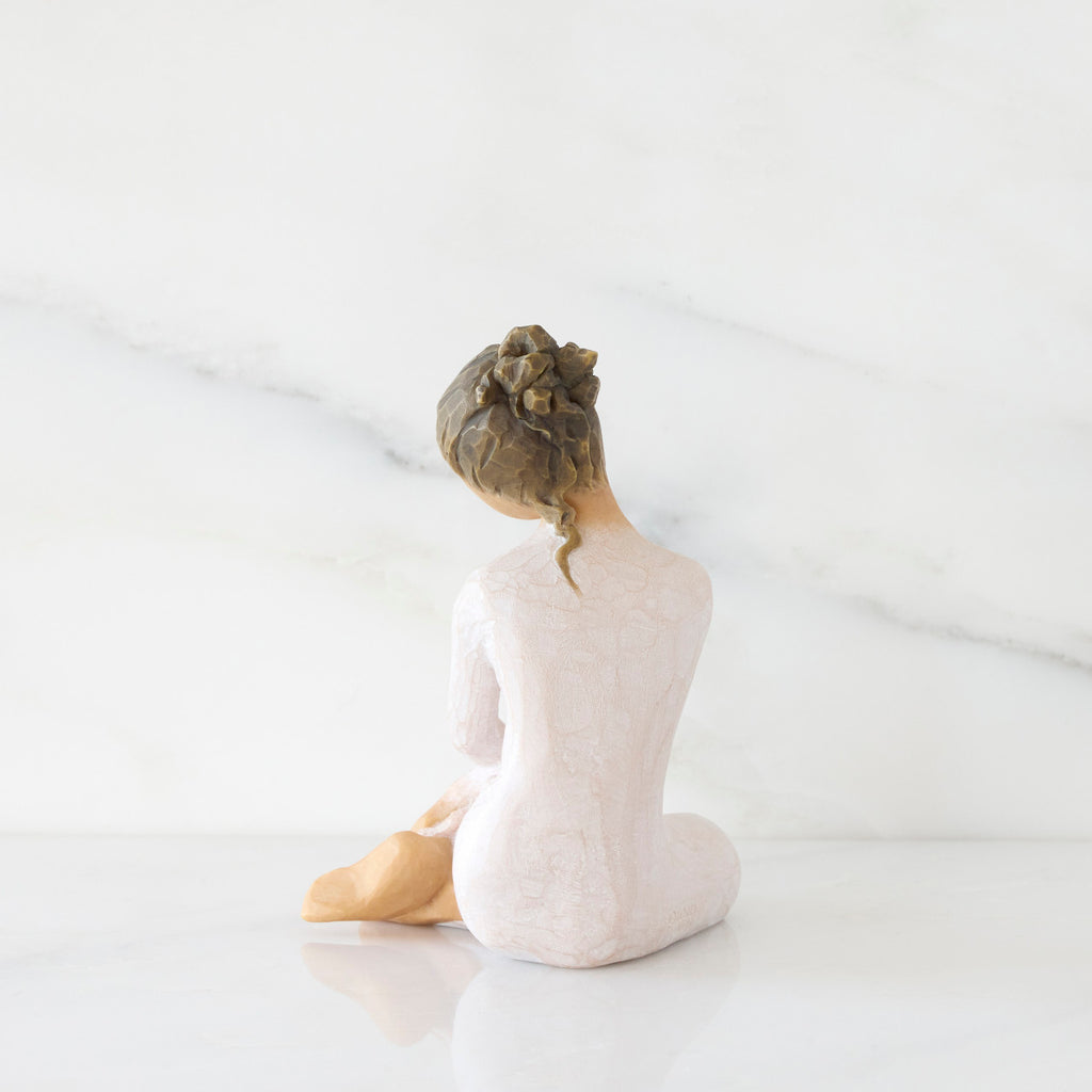 Back view: seated figure in cream dress with crossed arms