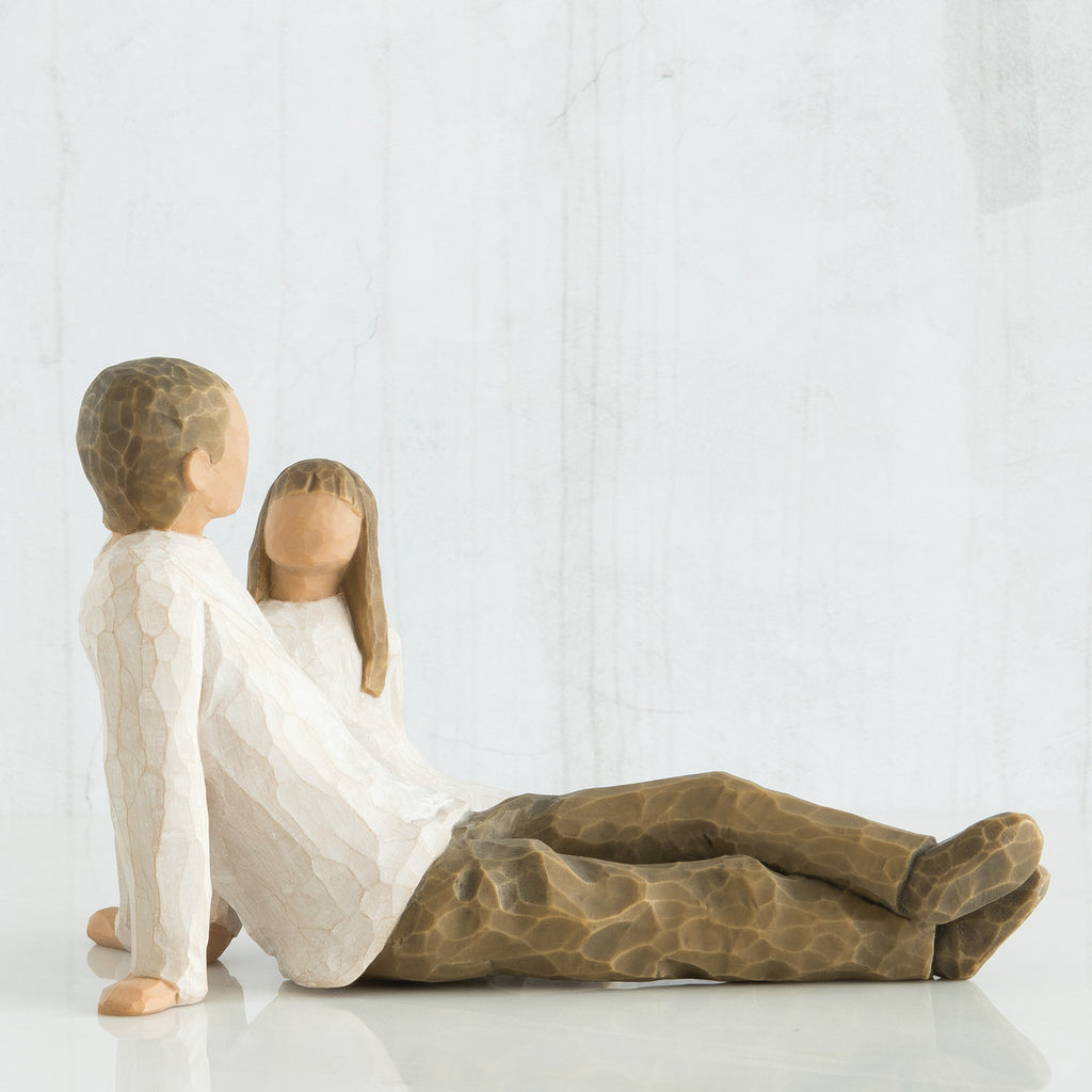 Man and woman figurine in white with brown pants sitting looking at one another