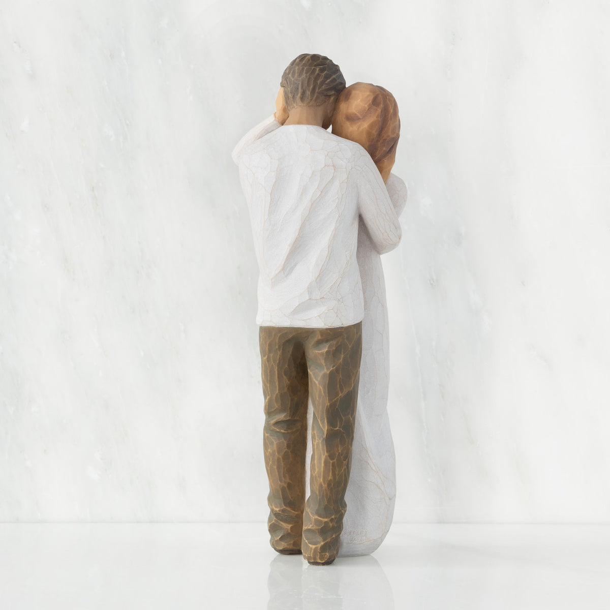 Back view of couple, standing with arms around each other. Woman has lighter skin and hair; man has darker skin and hair.