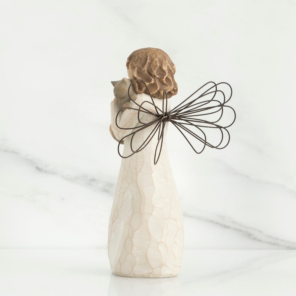 Back view of brunette angel figurine in white dress holding grey cat