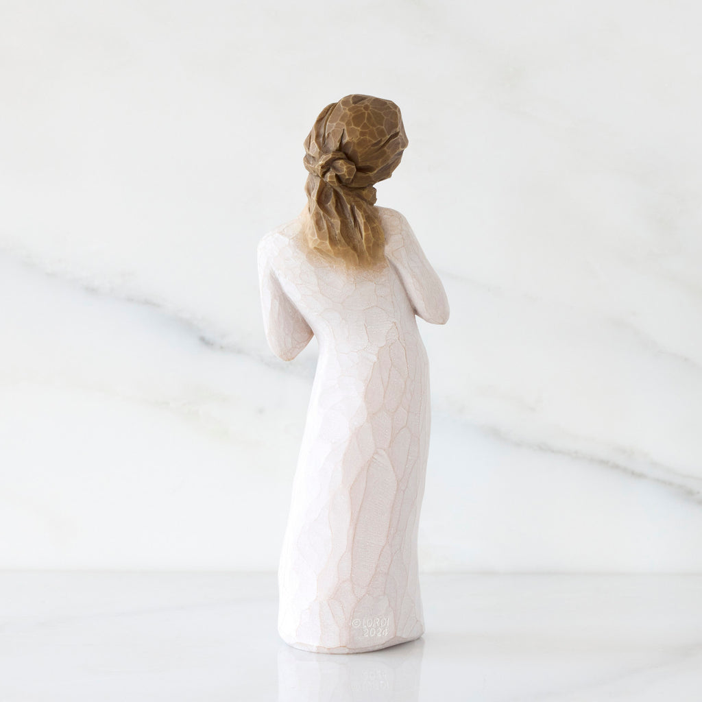 Back view: Standing figure in cream dress with hands to heart in empathetic gesture