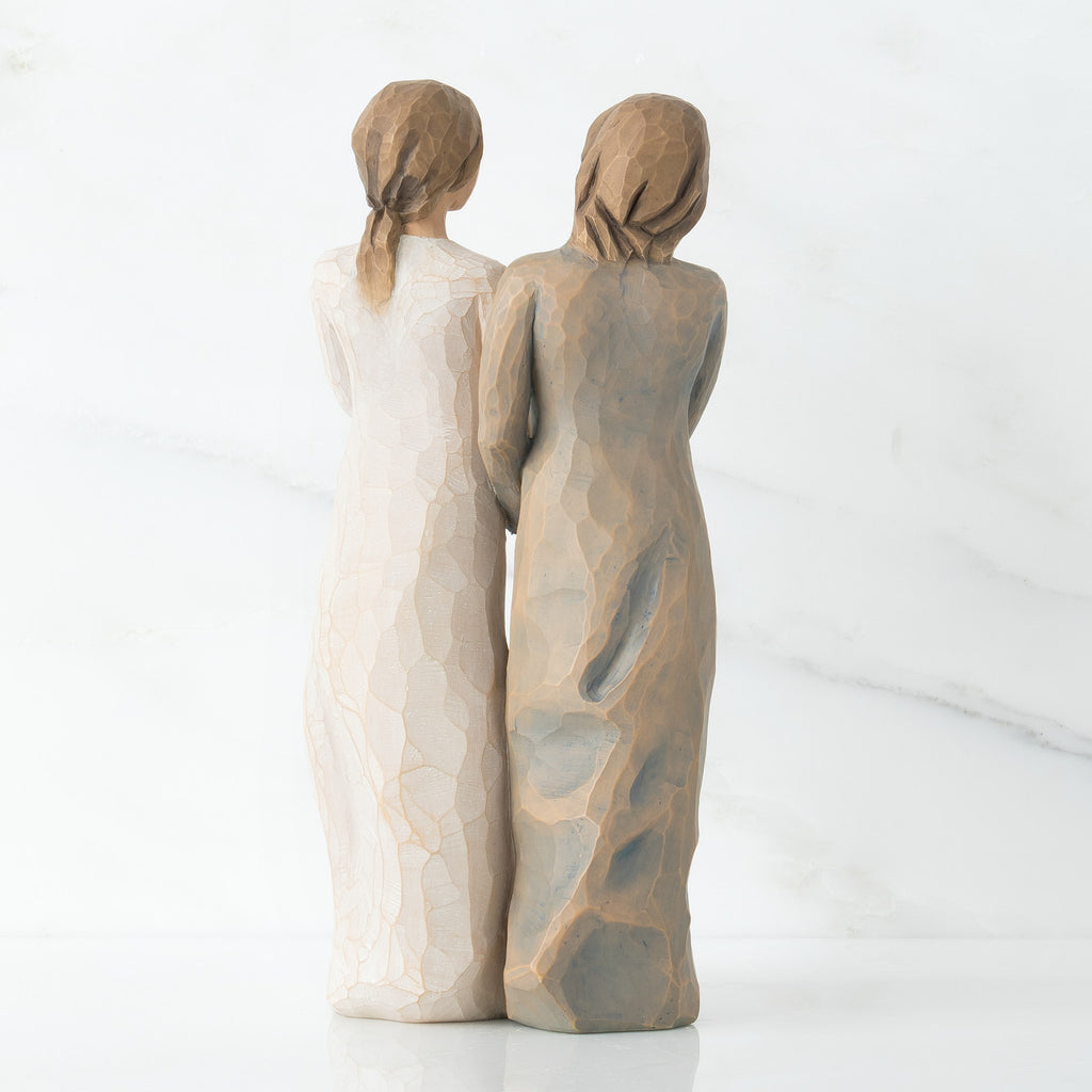 Back view of two woman figurines - one is in white, one is in brown
