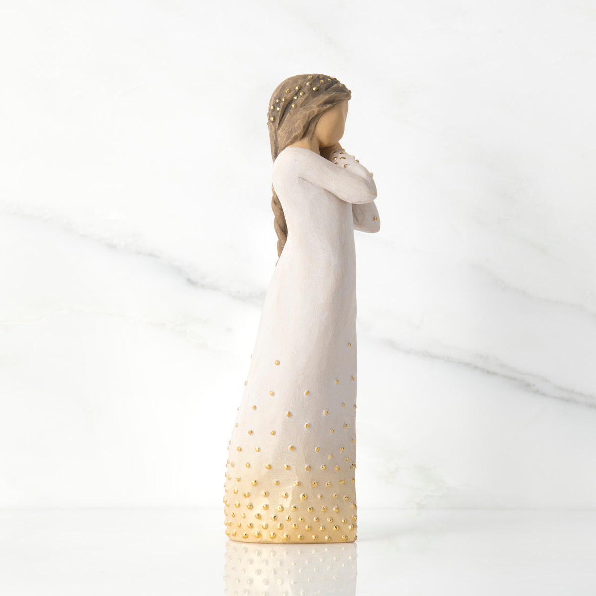 Right-facing view, standing figure in cream dress, holding arms to face in wistful gesture. Hair and dress embellished with gold dots