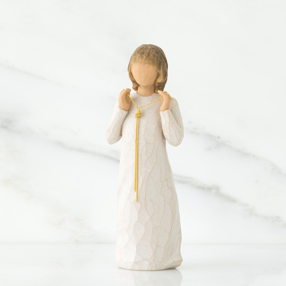 Small girl figurine wearing white dress with long gold chain holding her hands to her face