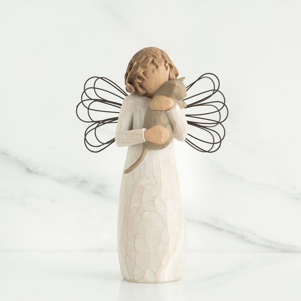 Faceless angel figurine facing forward holding grey cat wearing white dress and black wire wings