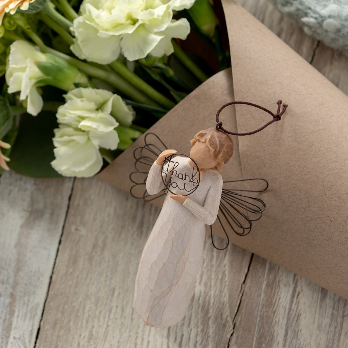 Willow Tree Just for You Ornament, 4”h hand-painted resin angel ornament in cream dress with wire wings, holding wire circle with 'thank you' written in wire, laying with floral bouquet