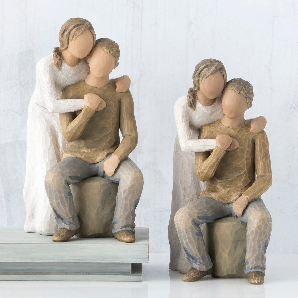 Set of two man and woman figurines - man is in brown sitting, woman is in white standing over him with arms on his shoulders
