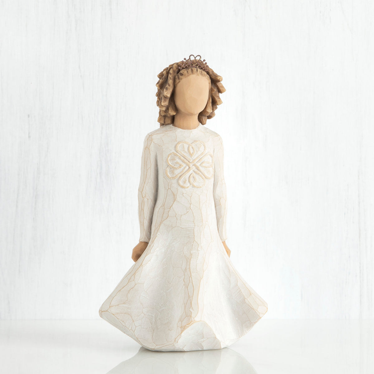 Faceless girl figurine with brown curly hair wearing white dress facing forward