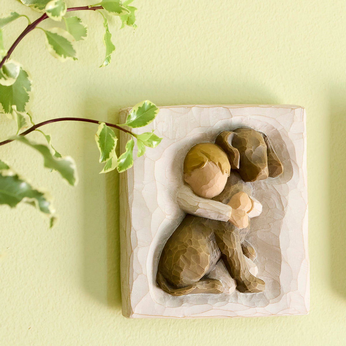 Willow Tree Hug Plaque, 4”sq x .5”d hand-painted resin bas-relief carving of small boy in cream shirt, hugging large dark dog, keyhole hanger for wall display