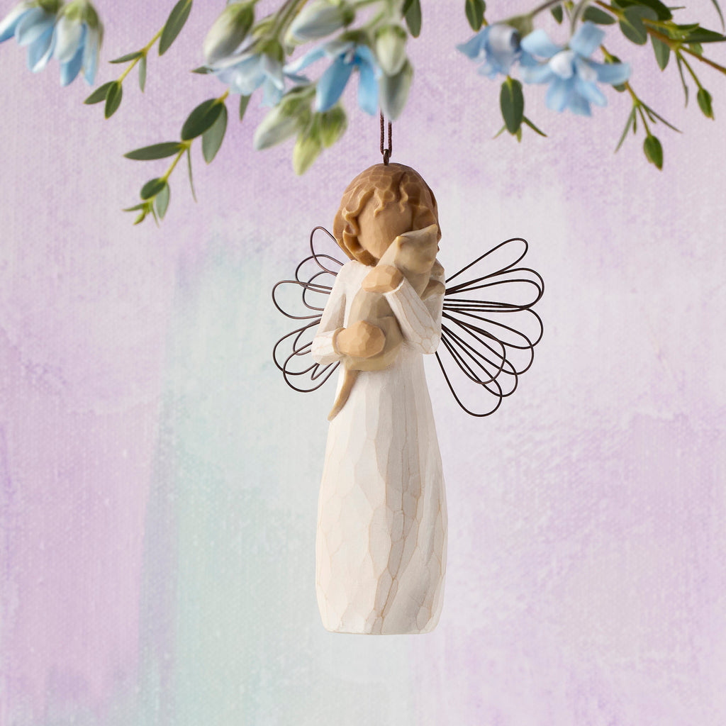 Willow Tree With affection Ornament, 4.5”h hand-painted resin figure in cream dress with wire wings, holding gray cat, brown elastic cord, hanging in front of lavender painting