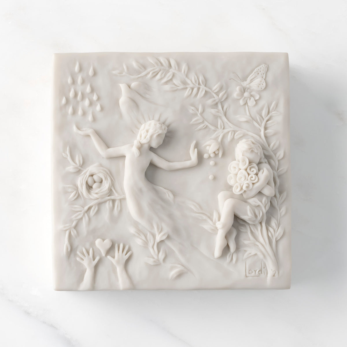 Close-up of white resin box; lid carved with figural and organic imagery