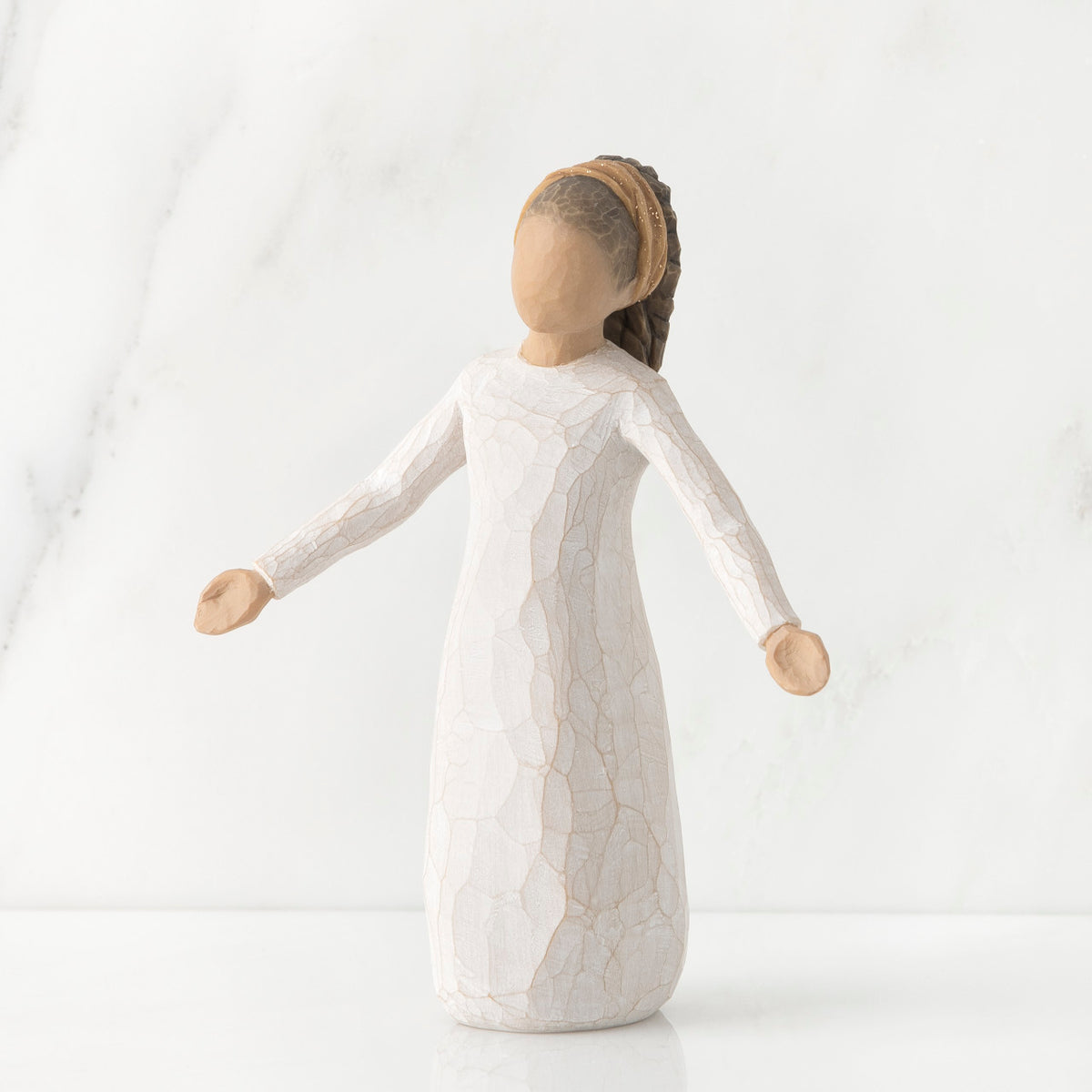 Young faceless girl figurine standing wearing all white dress with her arms out