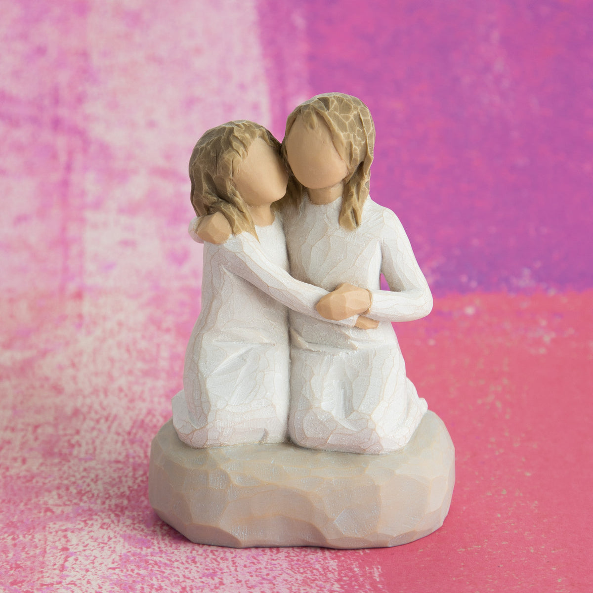 Willow Tree Sister mine, 4”h hand-painted resin figure of two girls in cream dresses, kneeling with arms around each other, in front of vibrant pink painting