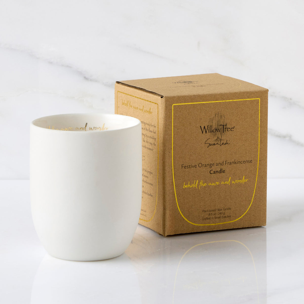 Filled scented candle with unglazed off-white tapered cylinder vessel, sentiment written in gold inside rim, plant-based wax blend, all-cotton wick, shown with packaging