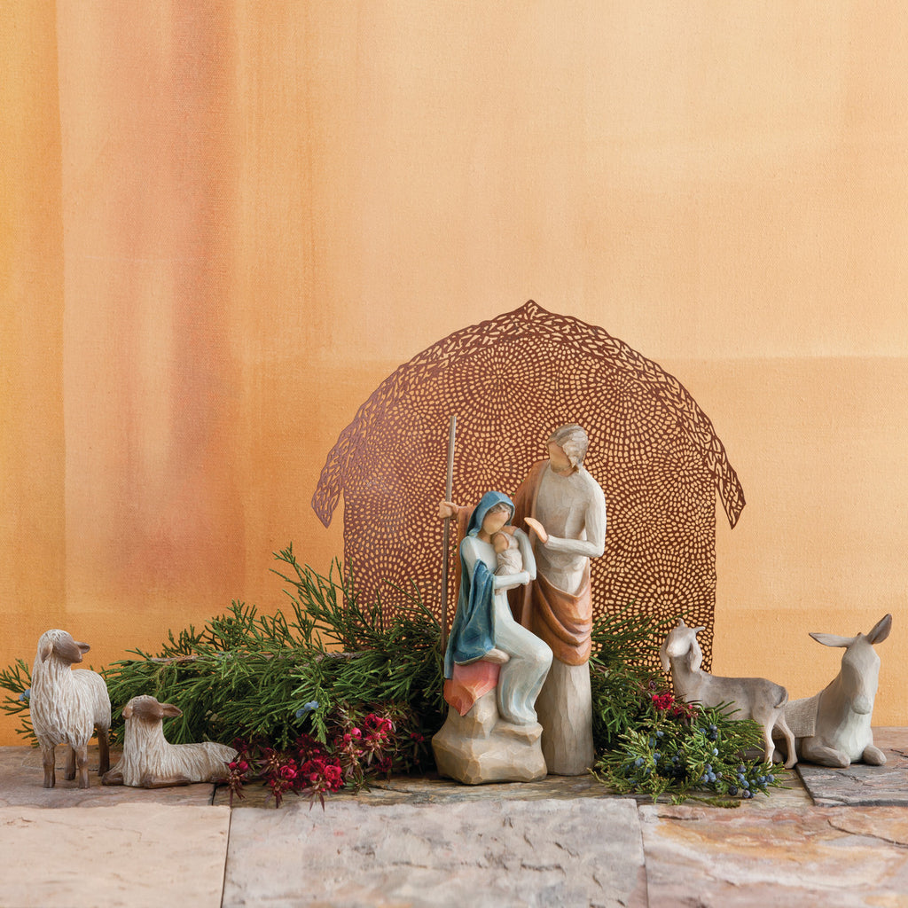 Far view of nativity scene figurines sitting on rock with brown barn in the background