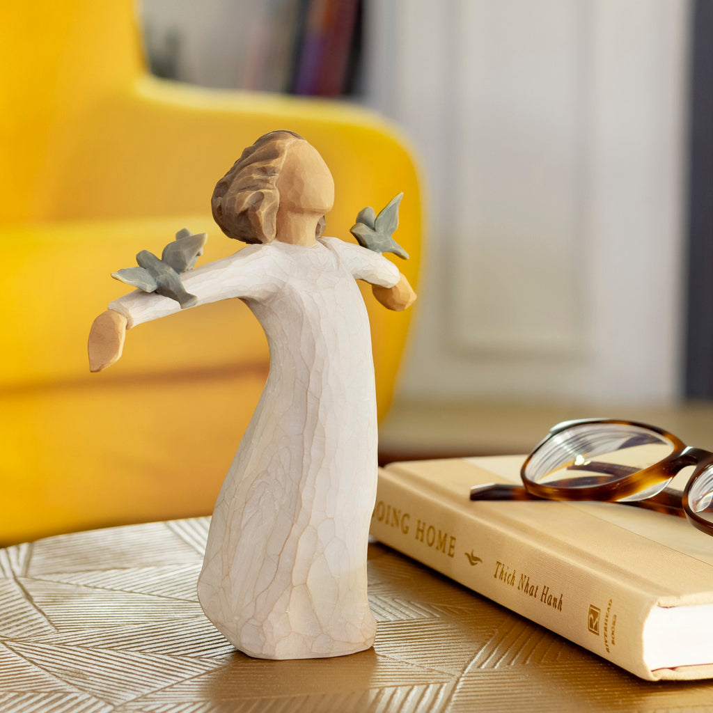 Willow Tree Happiness, 5.5”h hand-painted standing resin figure in cream dress, three bluebirds perched on outstretched arms, on table with book