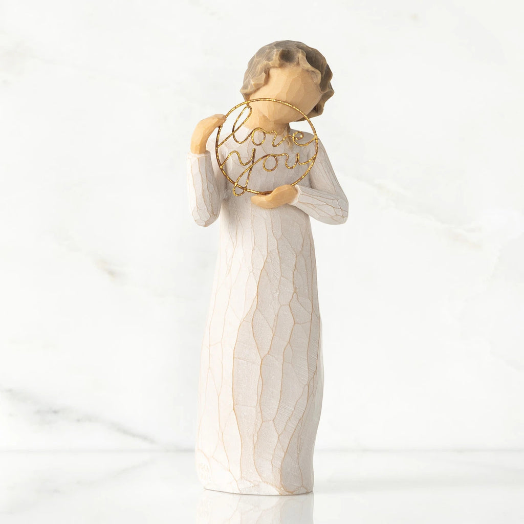 Front view, standing female figure in cream dress, holding gold wire circle in which is written 'love you'