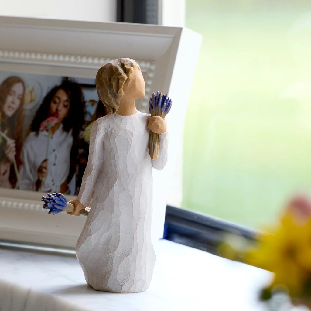 Willow Tree Lavender Grace, 5.5”h hand-painted standing resin figure in cream dress, holding two bundles of lavender flowers - one in raised hand, one at her side, on windowsill